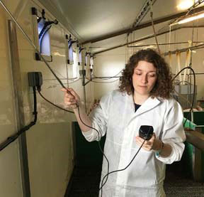 Undergraduate-on-placement, Liv Hartshorn, checks the inlet airspeed in a piggery during a visit for a routine service.