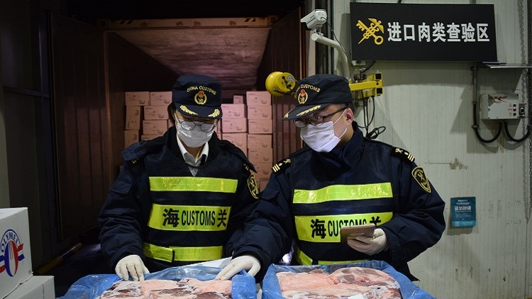 Customs officers inspect imported frozen pork products. Photo credit: Jiang Songqi
